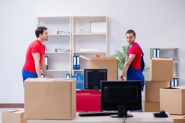 Movers arranging office furniture and boxes